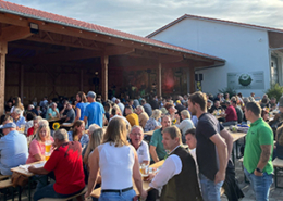 Titelbild: Aufnahme vom Unterreiner Bierfest mit vielen Menschen, die halb-überdacht auf Bierbänken mit Biertischen sitzen.
