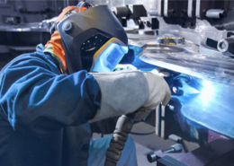 Titelbild: Mensch mit Schutzmaske und Schutzanzug beim Schweißen