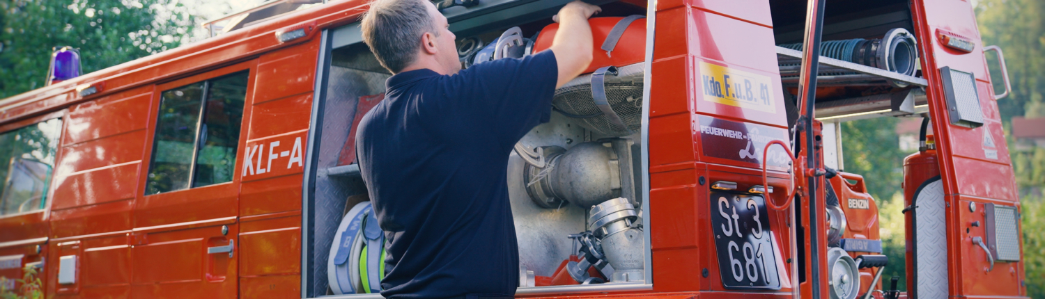 Steyr-Puch-Pinzgauer als Feuerwehrauto auf der Seite geöffnet. Mann entnimmt Feuerwehrutensilien